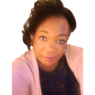 Pearline Nelson-Stephens a woman with styled hair, wearing a pink blazer and dark top, looks directly at the camera.